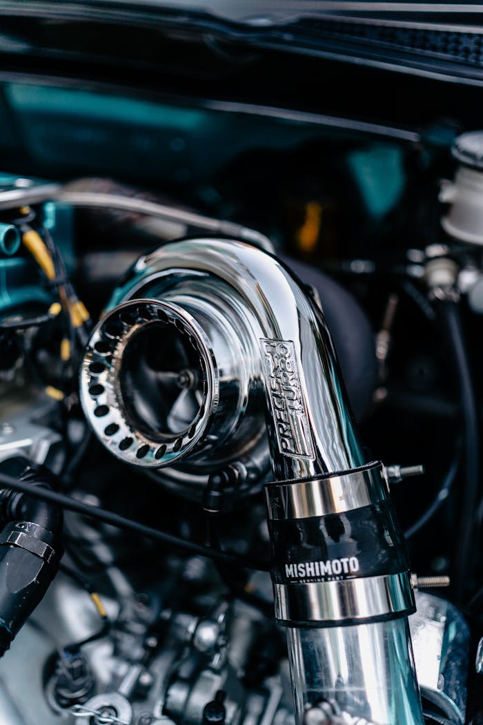 Services Detailed shot of a chrome turbocharger in a car engine bay, reflecting light.